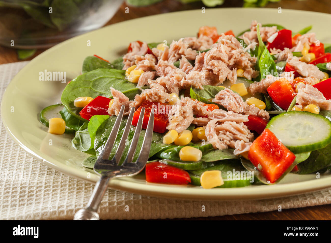 Salade d'épinards frais avec du thon, concombre, maïs, et paprika rouge sur une assiette. Matières premières alimentaires sains concept. Banque D'Images