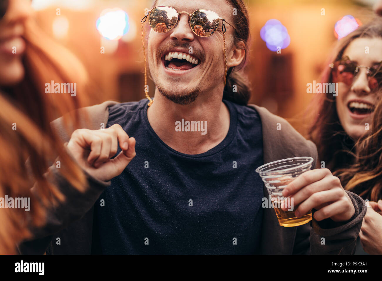 Jeune homme heureux avec des amis danser au festival de musique. Les jeunes ayant un grand temps à fête de la musique. Banque D'Images