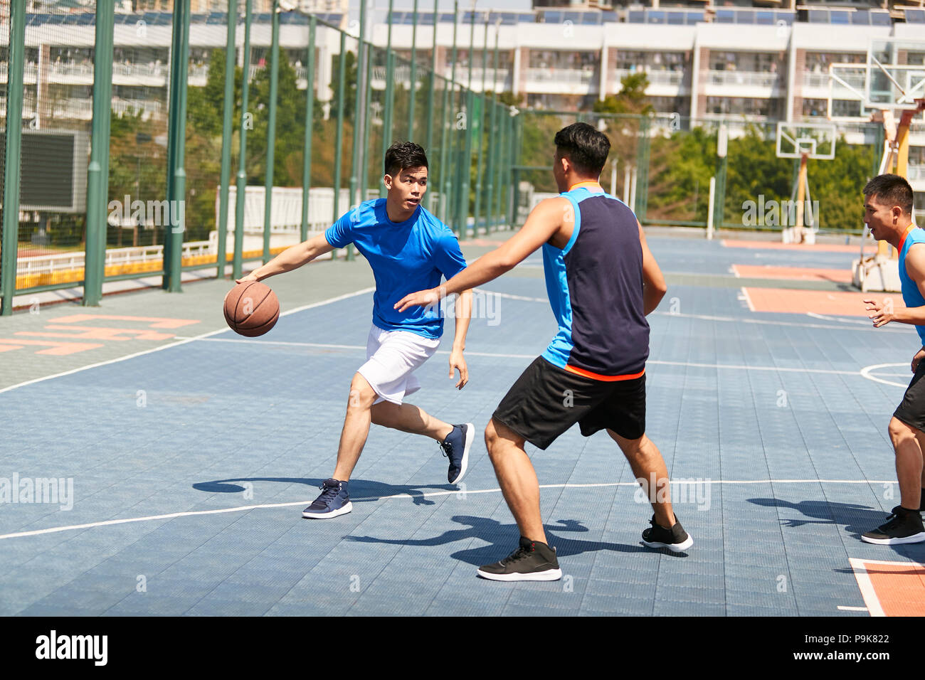 Les jeunes joueurs adultes asiatiques jouant au basket-ball sur une cour. Banque D'Images