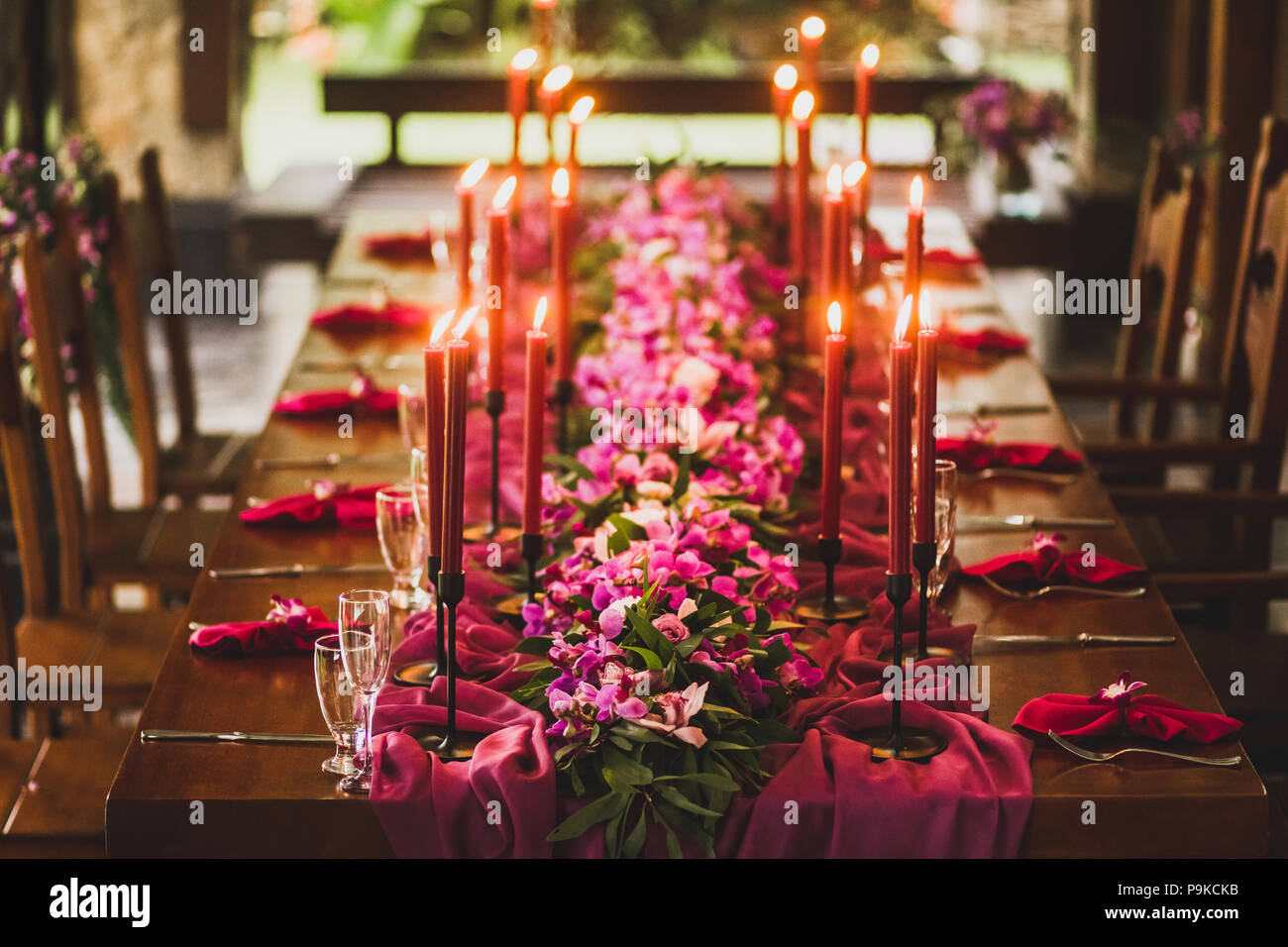 Table de mariage en bois décoré de bougies rouge, rose et violet tissu d'orchidées. Dîner romantique dans la soirée familiale Banque D'Images