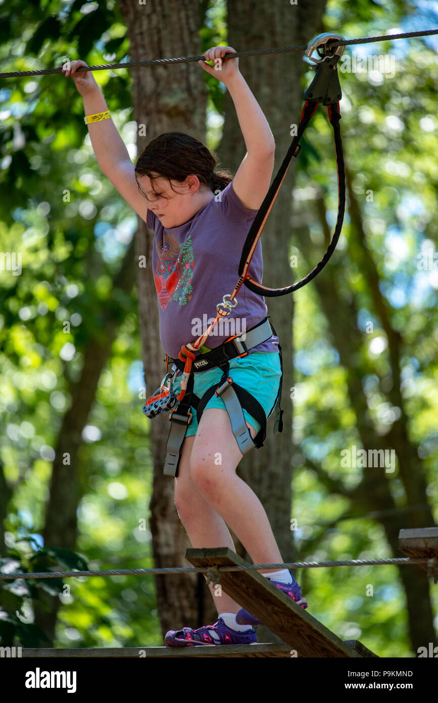 Portrait d'une belle jeune fille sur une corde entre les arbres du parc. Activités d'été pour enfants. Banque D'Images