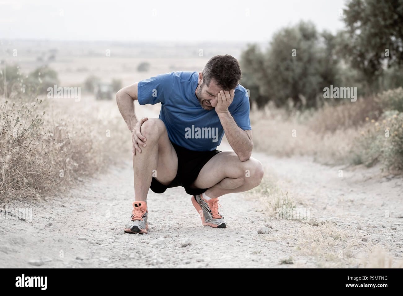 Les jeunes sport homme avec de fortes jambes athlétiques tenant le genou avec ses mains dans la douleur après avoir subi une lésion musculaire au cours d'un entraînement en cours de formation dans l'ASPHA Banque D'Images