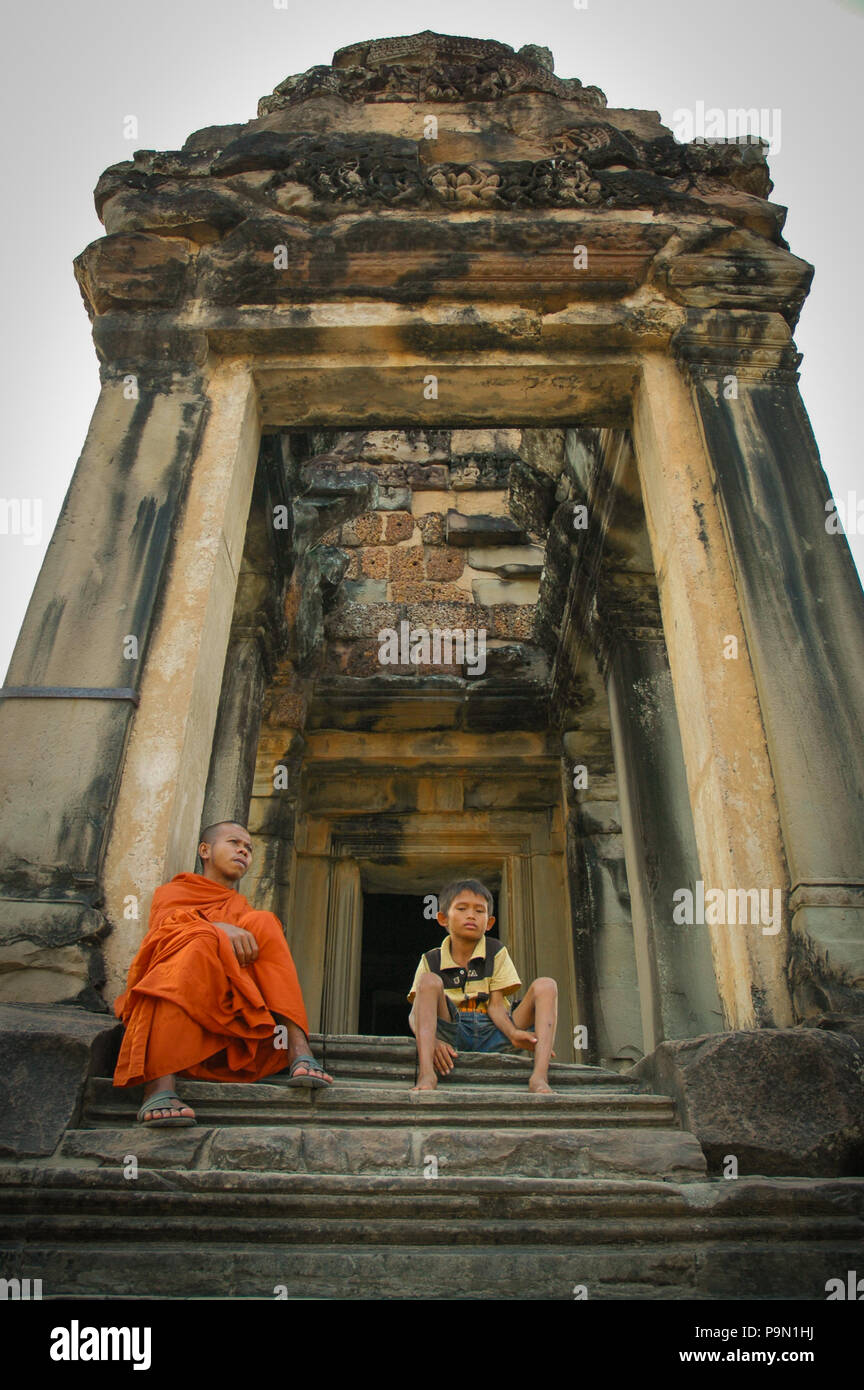 Un moine et un enfant assis à une structure de la bibliothèque dans l'enceinte d'Angkor Wat, la province de Siem Reap, au Cambodge. Banque D'Images