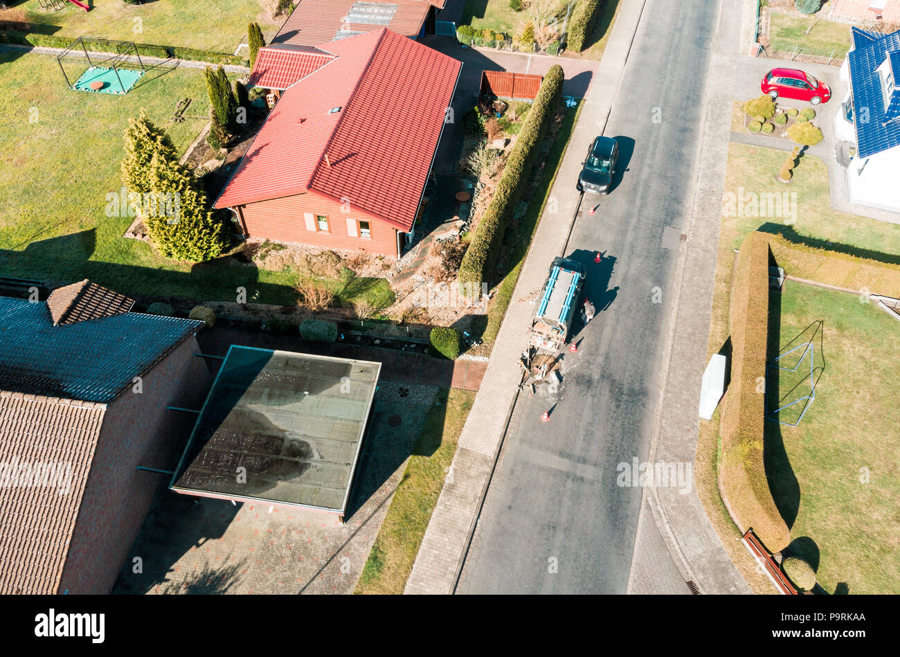 Vue aérienne d'une simple maison individuelle sur une route asphaltée gray village road, sur lequel un ouvrier n'effectue des travaux de maintenance, faites avec drone Banque D'Images