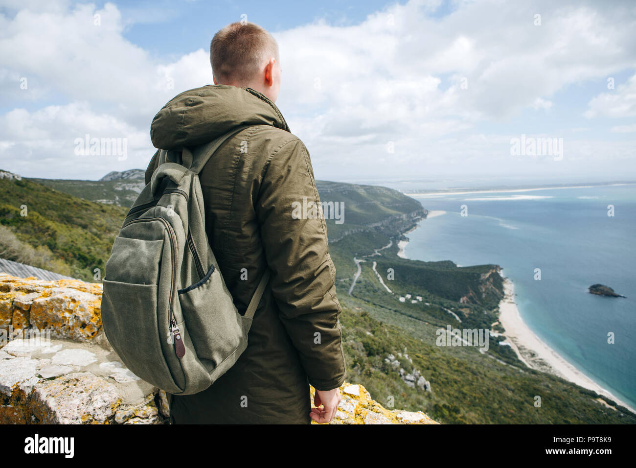 Un touriste ou voyageur avec un sac à dos est debout au sommet d'une colline et admirer la vue magnifique sur l'océan ou sur la mer. La marche ou la randonnée. Banque D'Images