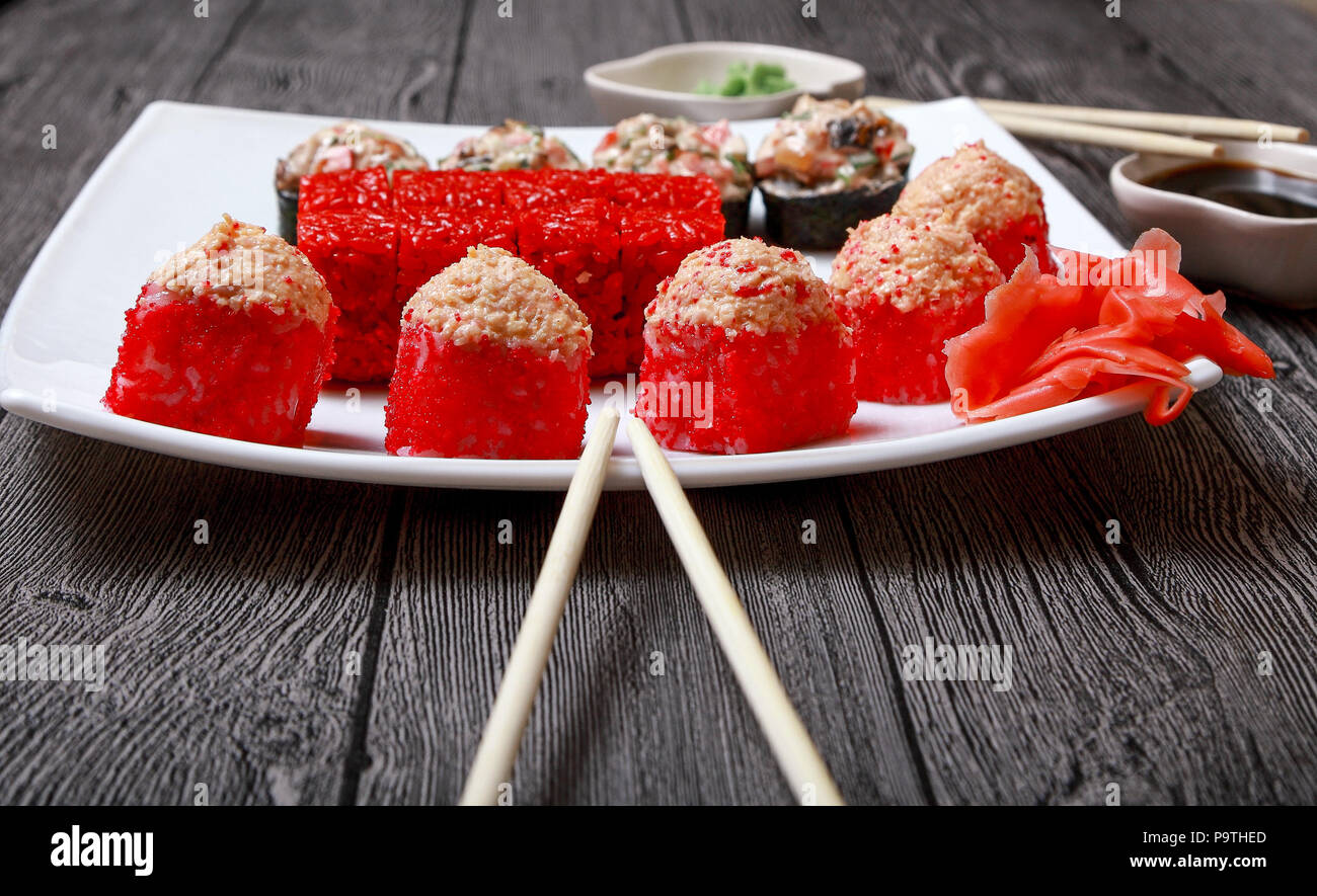 La cuisine japonaise. Sur la plaque sont différents rouleaux rouge, sushi, gingembre et des bâtonnets de bois. Banque D'Images