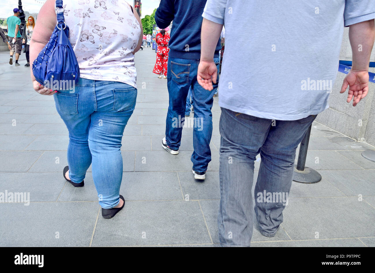 Deux inconnus le surpoids / obésité marcher le long de la South Bank, Londres, Angleterre, Royaume-Uni. Banque D'Images