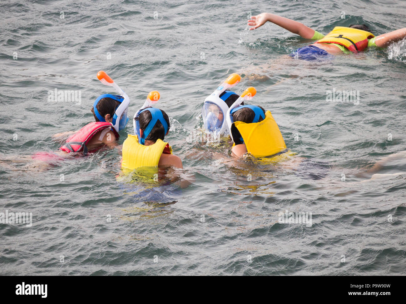 Aides à la flottabilité des enfants portant des masques faciaux avec tuba dans la mer. Banque D'Images