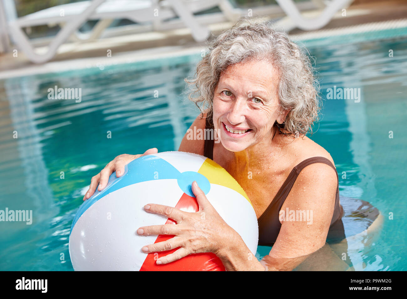 Happy senior couple vital est de jouer avec une balle dans la piscine en vacances Banque D'Images