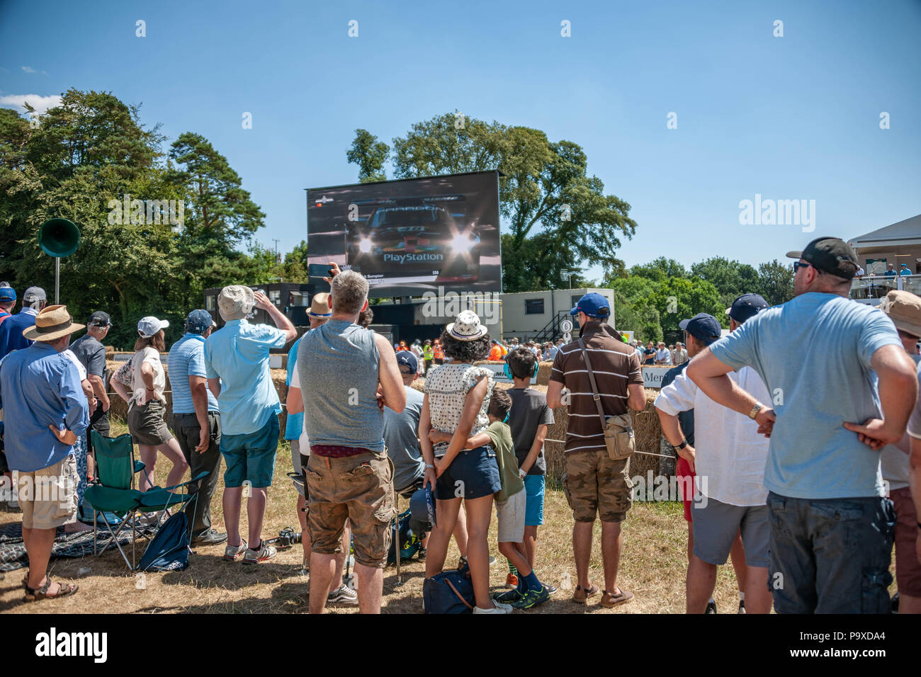 Spectateurs regardant cars race par et regarder sur grand écran au Goodwood Festival of Speed du Jubilé, anniversaire. Banque D'Images