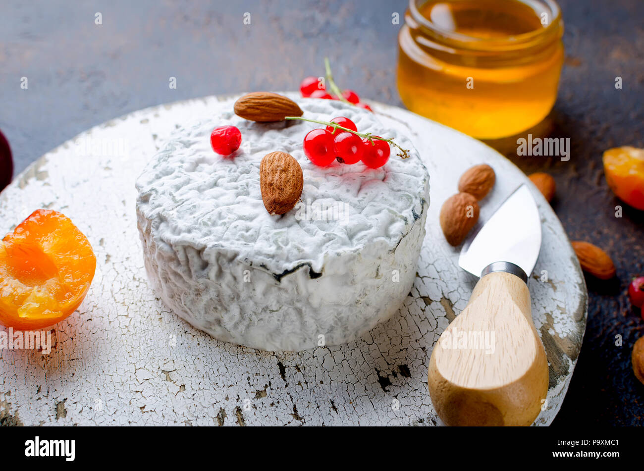 Tête ronde de fromage bleu avec du miel, de cassis, de fruits à coque et une bouteille de vin sur un tableau sombre, concept de gastronomie, fromage italien, romantique ev Banque D'Images