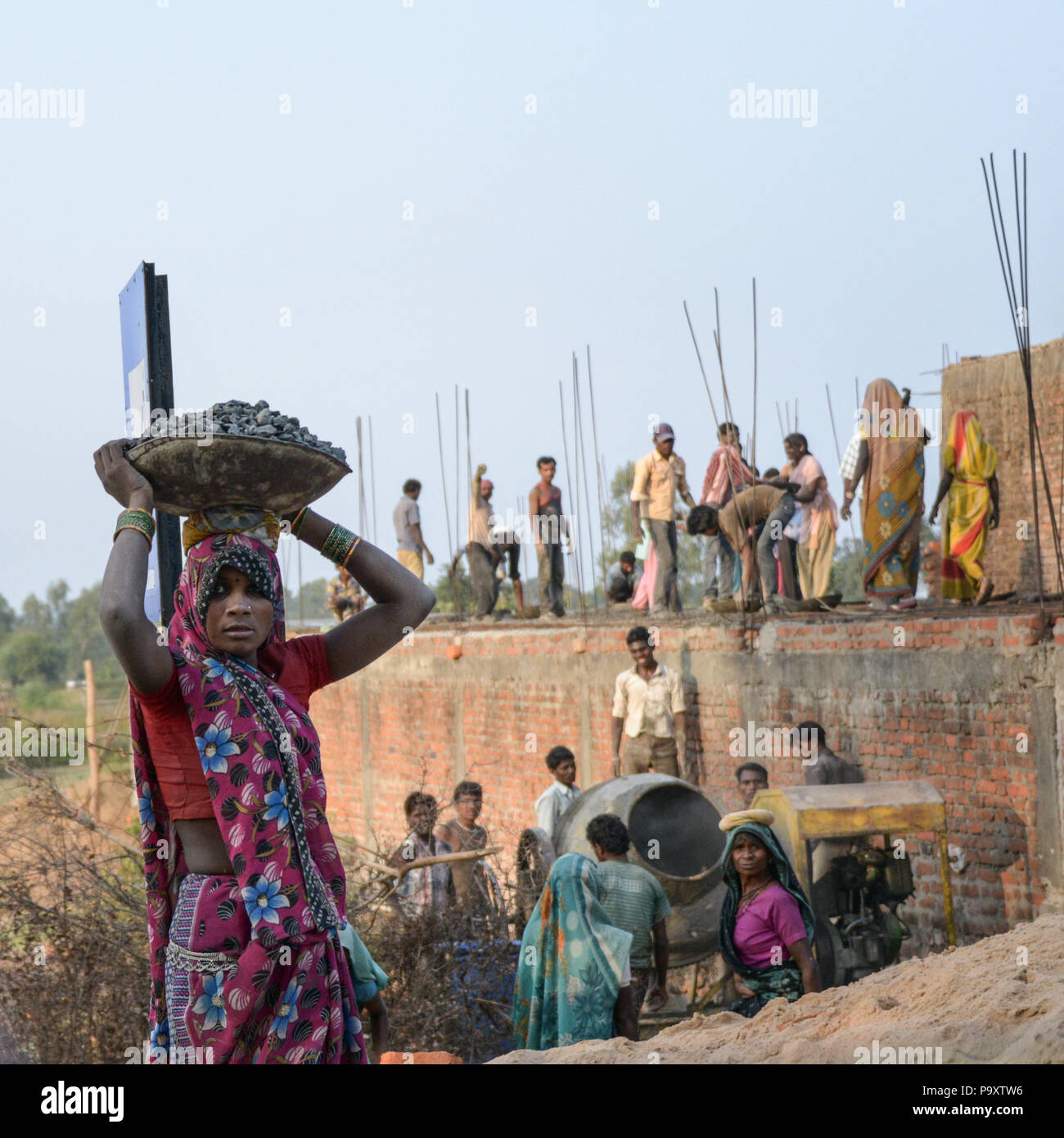 Un style de photo d'une femme indienne portant un panier sur sa tête avec les travailleurs du village sur un chantier dans l'arrière-plan Banque D'Images