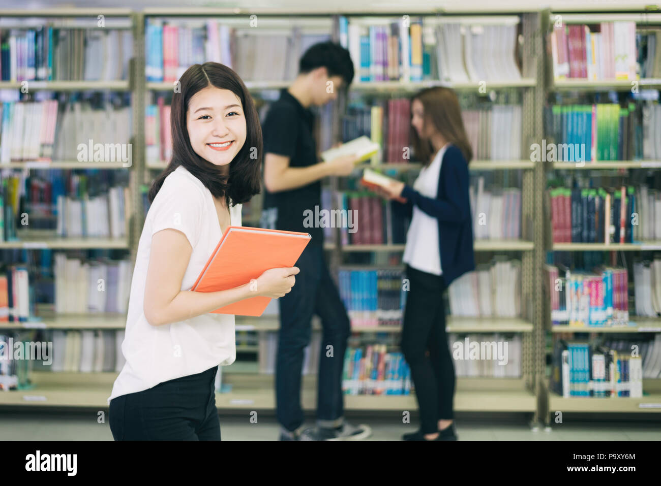 Groupe d'étudiants asiatiques d'étudier ensemble dans la bibliothèque à l'université. Les étudiants universitaires. Happy girl smiling et reding livre. Banque D'Images