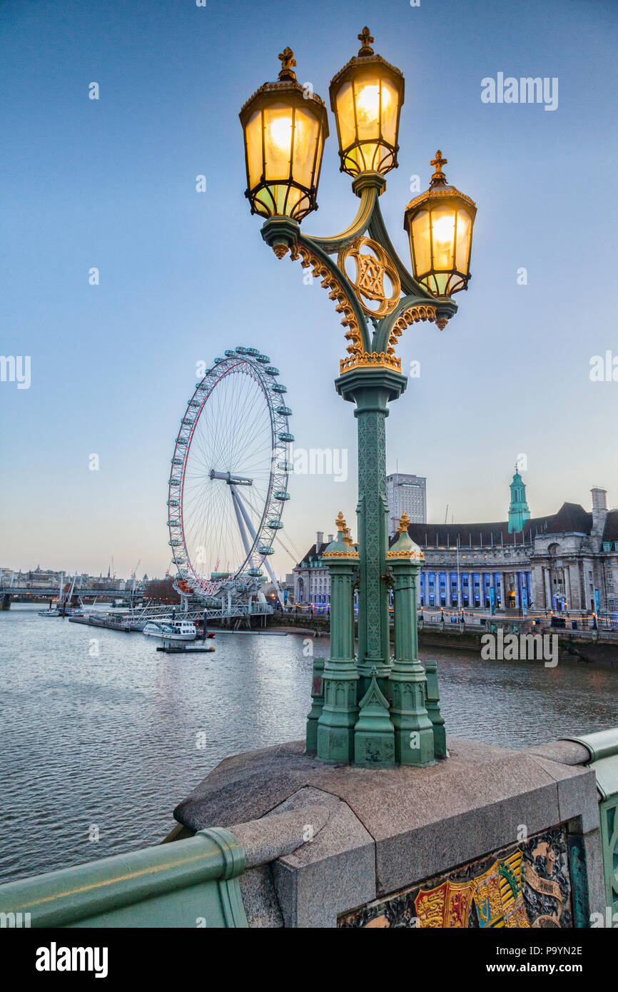 Une lampe standard sur le pont de Westminster, éclairé, avec le London Eye et le County Hall en arrière-plan. Banque D'Images