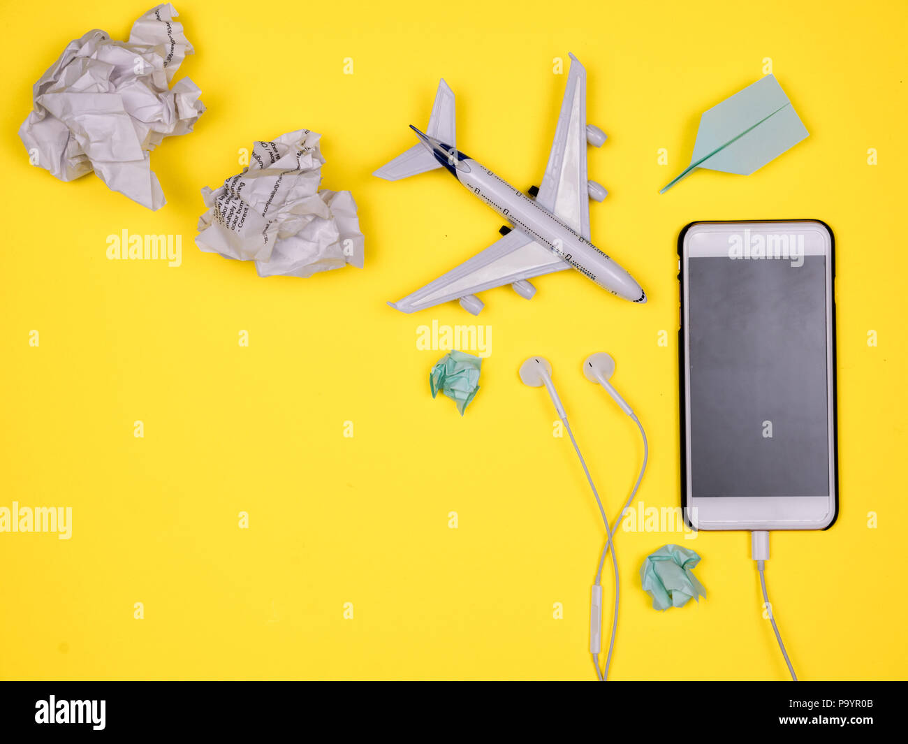 Smartphone, écouteurs, jouet avion, avion en papier et papier jeté Banque D'Images
