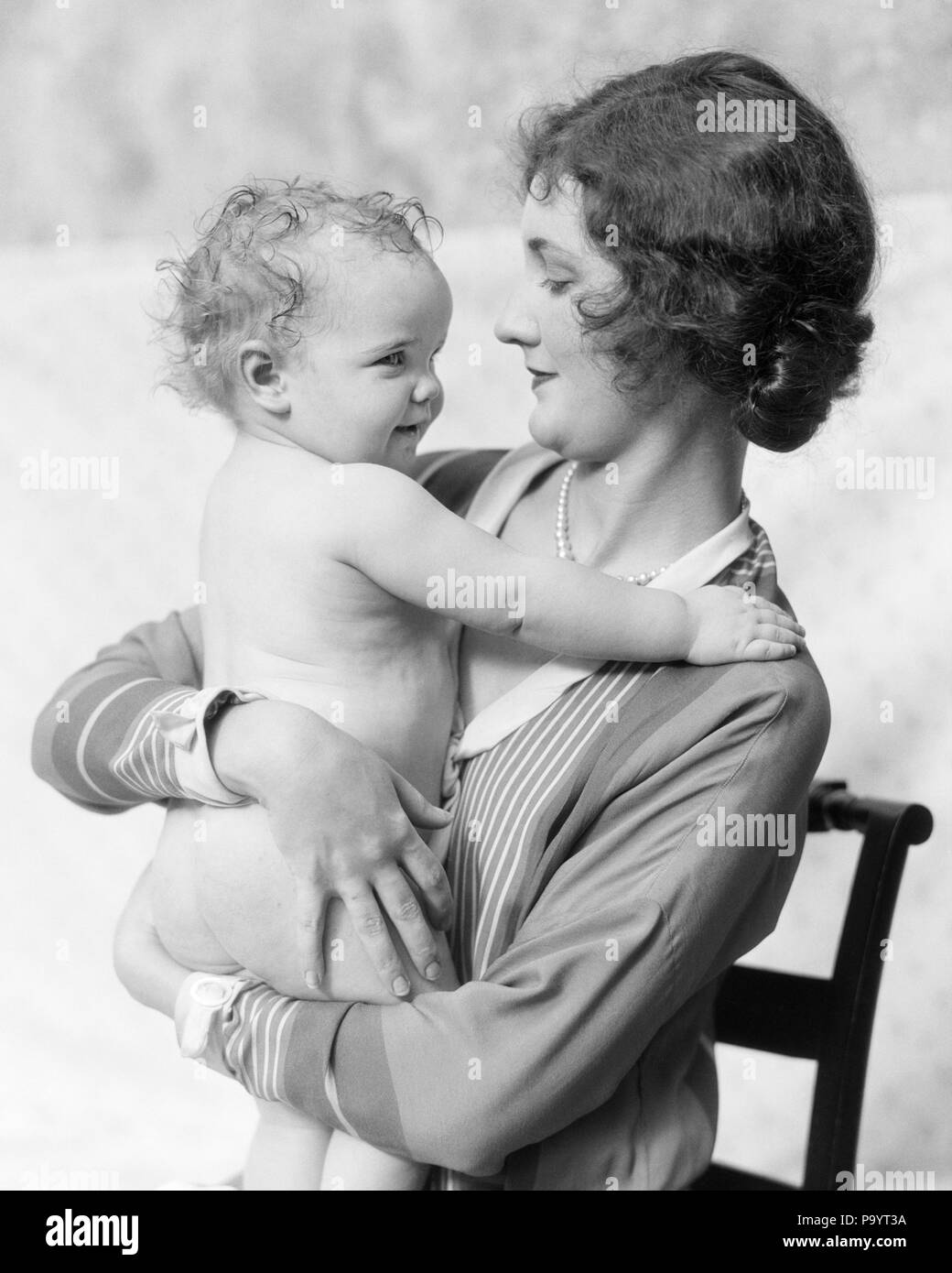 Années 1920 FEMME MOTHER SITTING IN CHAIR HOLDING SMILING BABY IN ARMS - b6492 HAR001 HARS, jeune adulte HEUREUX JOIE VIE FEMMES FIERS DE SANTÉ ACCUEIL demi-longueur de vie mesdames filles s'occupent des personnes de confiance de l'INSPIRATION DE FAIRE PLACE AU B&W BRUNETTE BIEN-ÊTRE LE BONHEUR DE JOYEUX SOURIRES FACE À FACE LES JEUNES MAMANS ÉLÉGANTES JOYEUSE CONNEXION TOGETHERNESS WOMAN NOIR ET BLANC DE L'ORIGINE ETHNIQUE CAUCASIENNE HAR001 old fashioned Banque D'Images