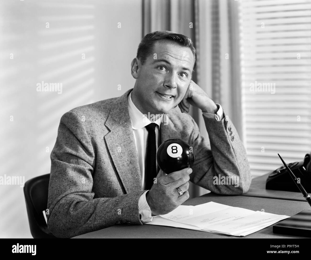 1950 Inquiets BUSINESSMAN SITTING AT DESK DERRIÈRE HUIT NOIR BALL LOOKING AT CAMERA - BX016818 CAM001 HARS NERVEUX risque d'expressions de l'entreprise B&W costume et cravate de vendre 8 OBSTACLE CAM001 BILLARD INCONVÉNIENT échapper aucune difficulté à échapper STUMPED HUIT ADULTES MI-VENDEURS MID-ADULT MAN 8 BALL NOIR ET BLANC DE L'ORIGINE ETHNIQUE CAUCASIENNE HUIT BALL Old Fashioned perplexe Banque D'Images