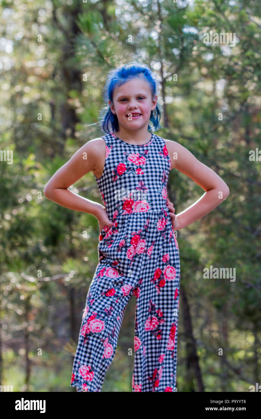 Atrtractive 8 ans, fille, dans les cheveux colorés, combinaison de saut est  teint bleu lumineux, à la caméra et au comité permanent dans les arbres.  Communiqué de modèle # 113 Photo Stock - Alamy