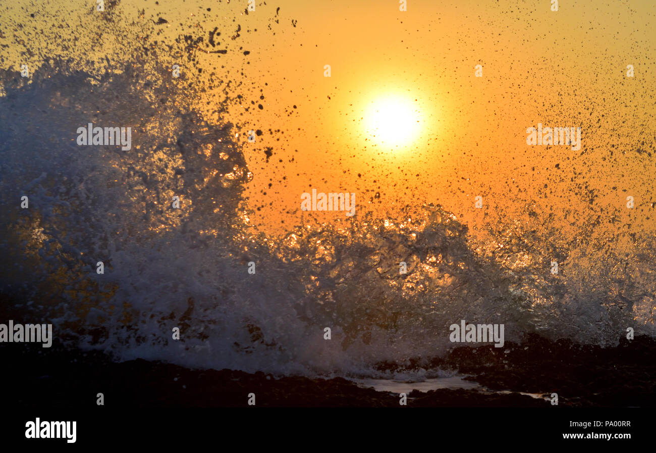 Les ondes de marée dans la mer d'Oman fracassant la plage rocheuse plage au coucher du soleil Banque D'Images