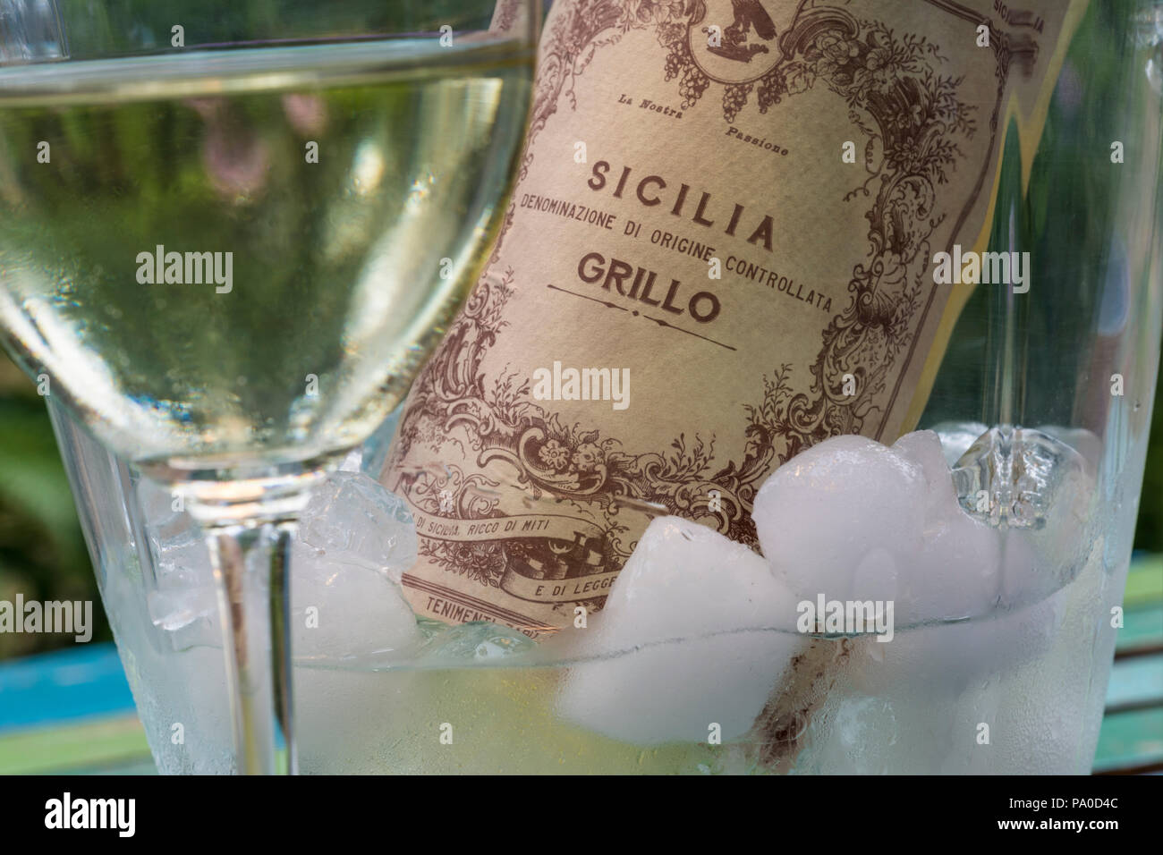 Bouteille de vin blanc sicilien DOC Grillo en glace avec verre coulé en premier plan en plein air jardin terrasse situation Italie Banque D'Images