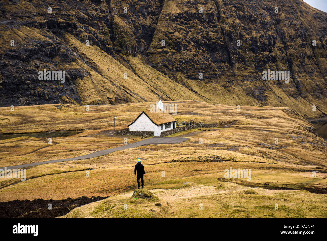 Vue arrière de l'homme debout près de toit de chaume maison, îles Féroé, Danemark Banque D'Images