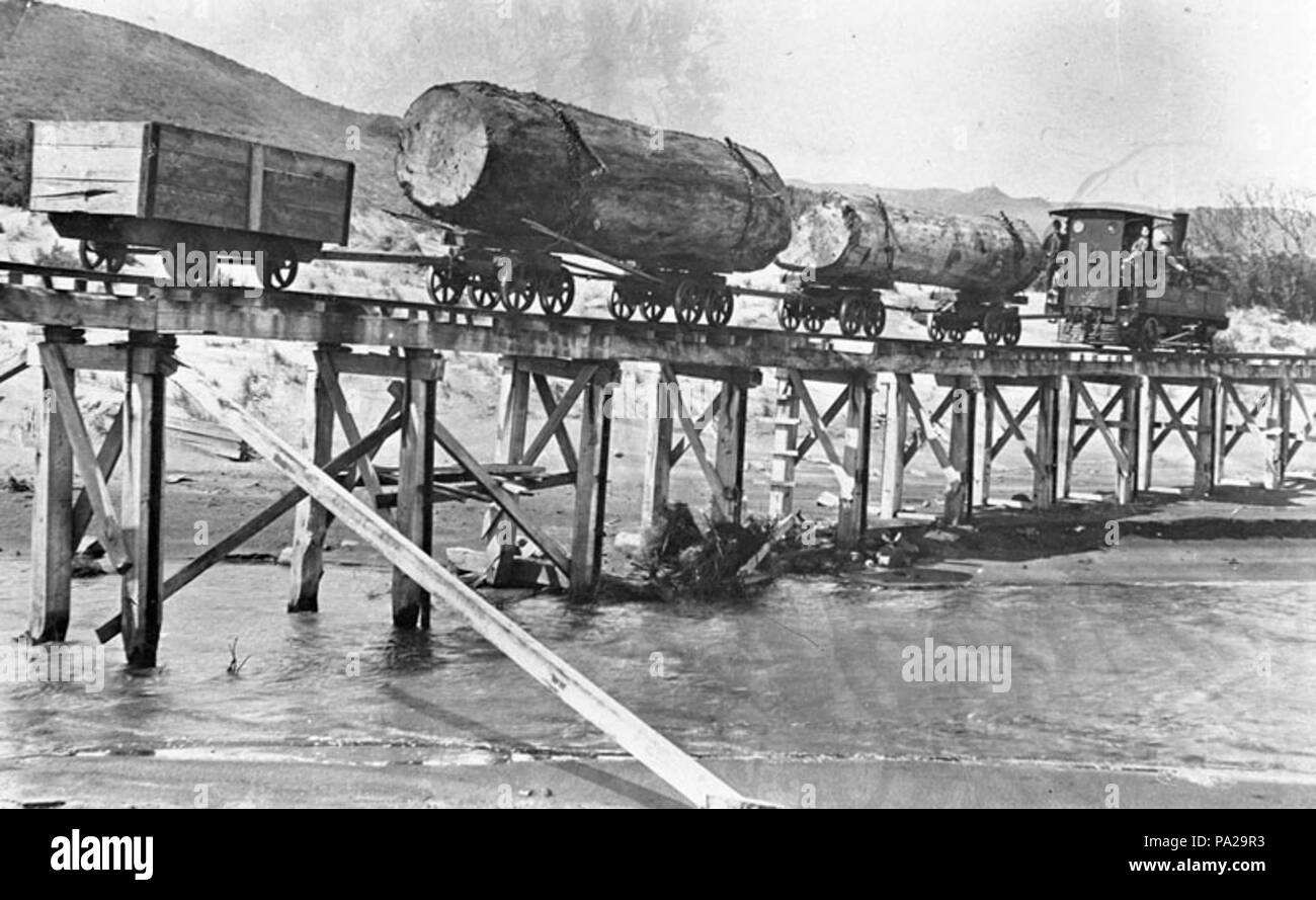 199 Piha, moteur de Tramway transportant deux bogies avec les journaux de kauri et un bogie de queue panier, traverse l'Wekatahi Creek sur un pont sur chevalets, North Piha beach Banque D'Images
