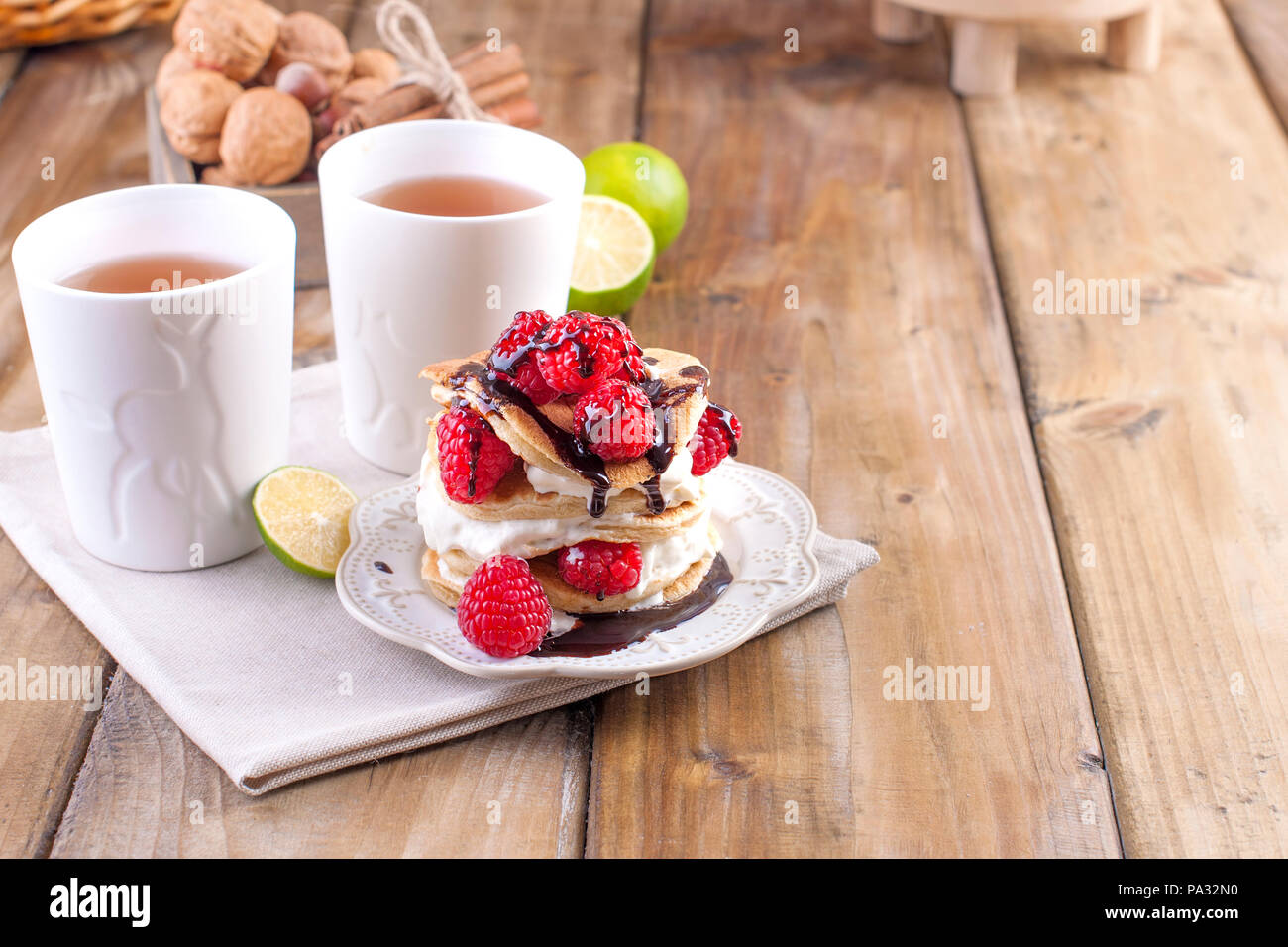 Sweet home avec punkcakes crème blanche et framboise rouge frais de baies. Deux verres de thé pour le petit-déjeuner. sur un fond de bois. l'espace libre pour le texte ou la publicité. Banque D'Images