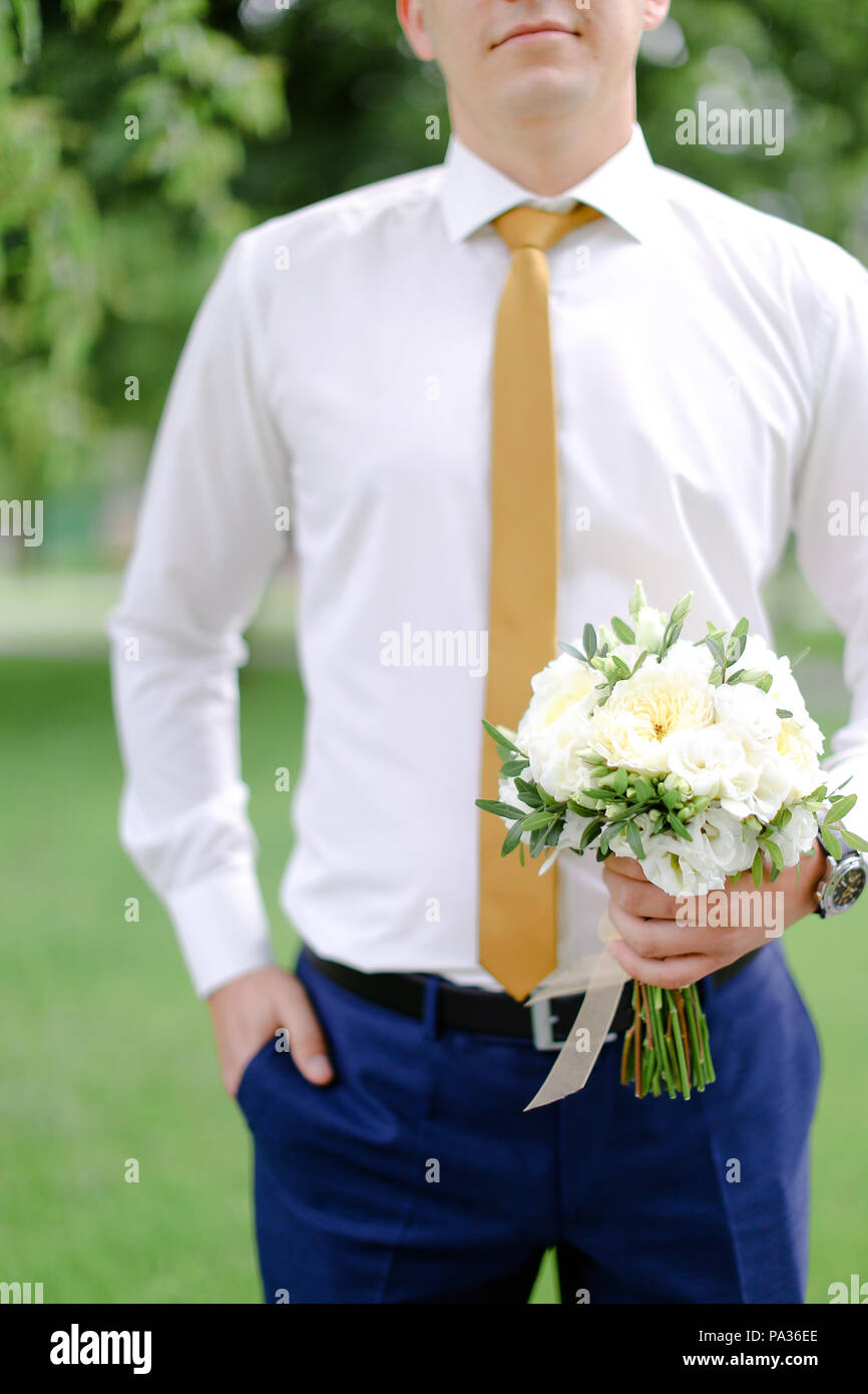 Les jeunes mariés maintenant bouquet de fleurs et portant chemise avec  cravate jaune Photo Stock - Alamy