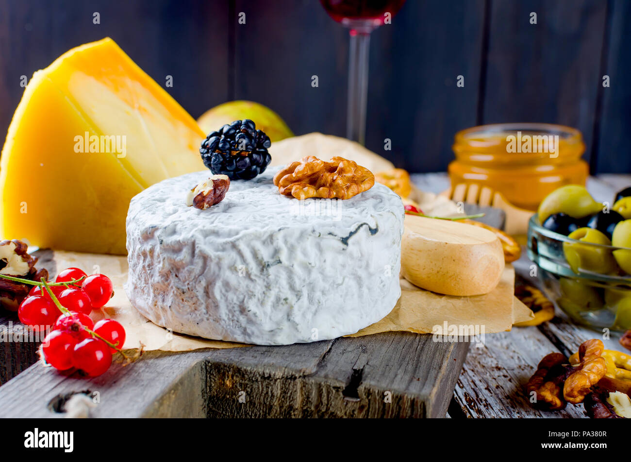 Tranches de fromage, fromage par la rouille, fromage à pâte dure, les olives, les noix, les arachides, le miel, un verre de vin, un dîner romantique, un repas pour les shurman Banque D'Images