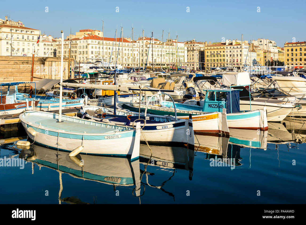 Le Vieux Port de Marseille, France, avec de vieux bateaux de pêche amarrés dans l'eau morte et les bâtiments du Quai des Belges baigné de lumière chaude. Banque D'Images