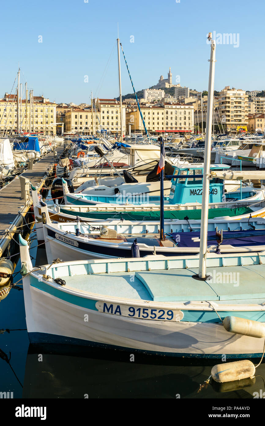 Le Vieux Port de Marseille, France, avec de vieux bateaux de pêche amarrés dans l'eau morte et la Basilique de Notre-Dame de la garde en haut de la colline. Banque D'Images