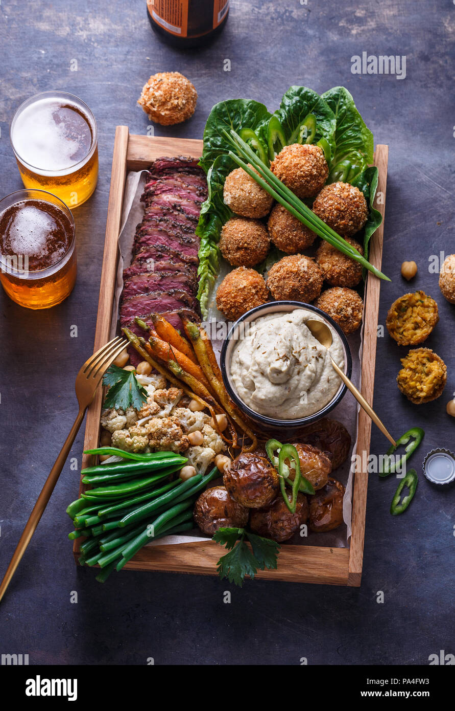 Le pastrami, falafel, babagahanoush, légumes et la bière dans une boîte en bois, copyspace Banque D'Images