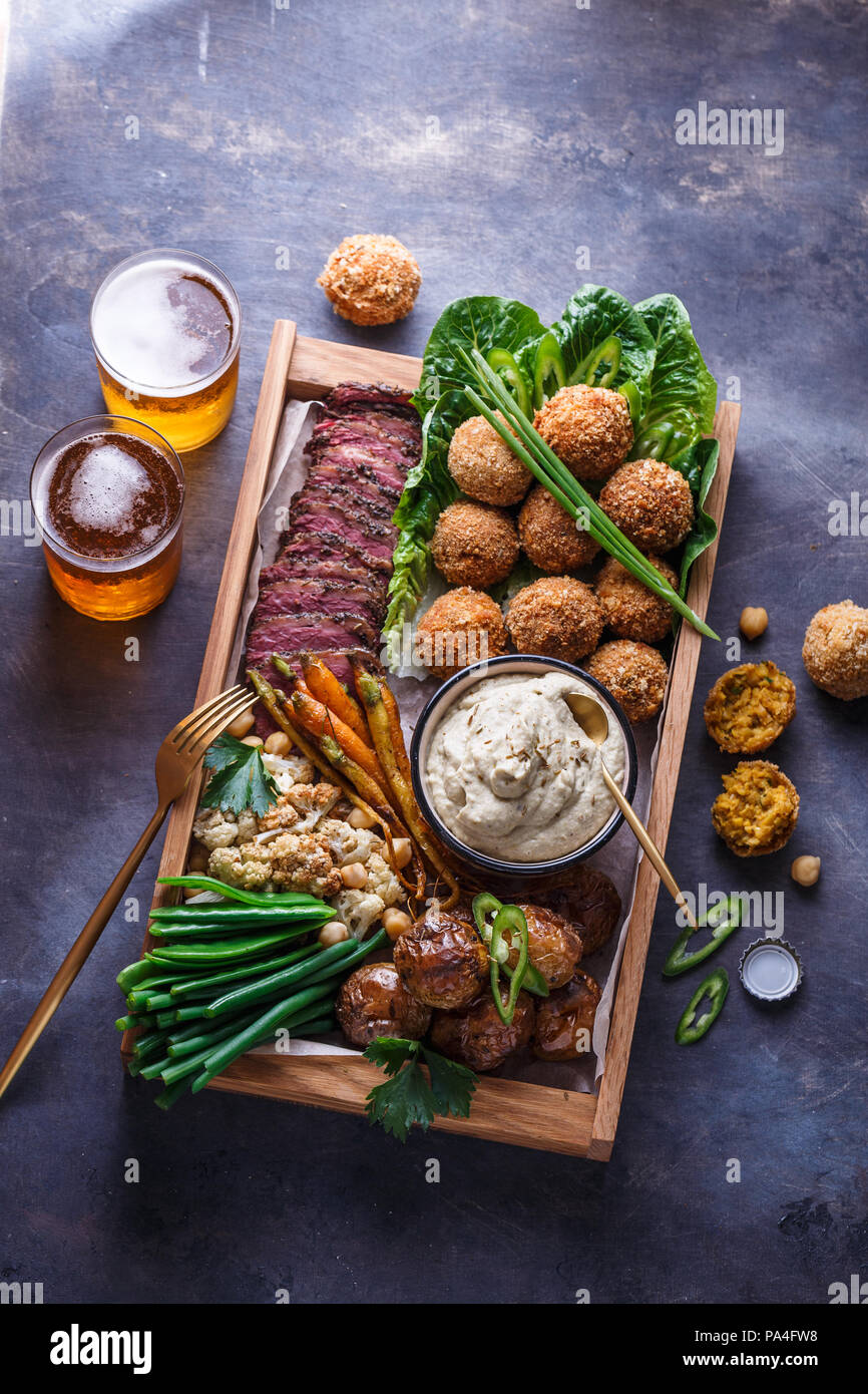 Le pastrami, falafel, babagahanoush, légumes et la bière dans une boîte en bois, copyspace Banque D'Images