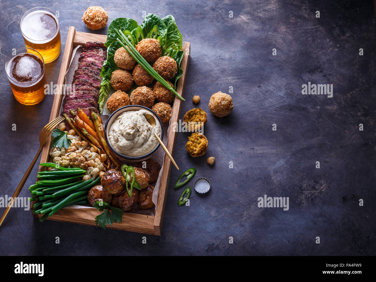 Le pastrami, falafel, babagahanoush, légumes et la bière dans une boîte en bois, copyspace Banque D'Images