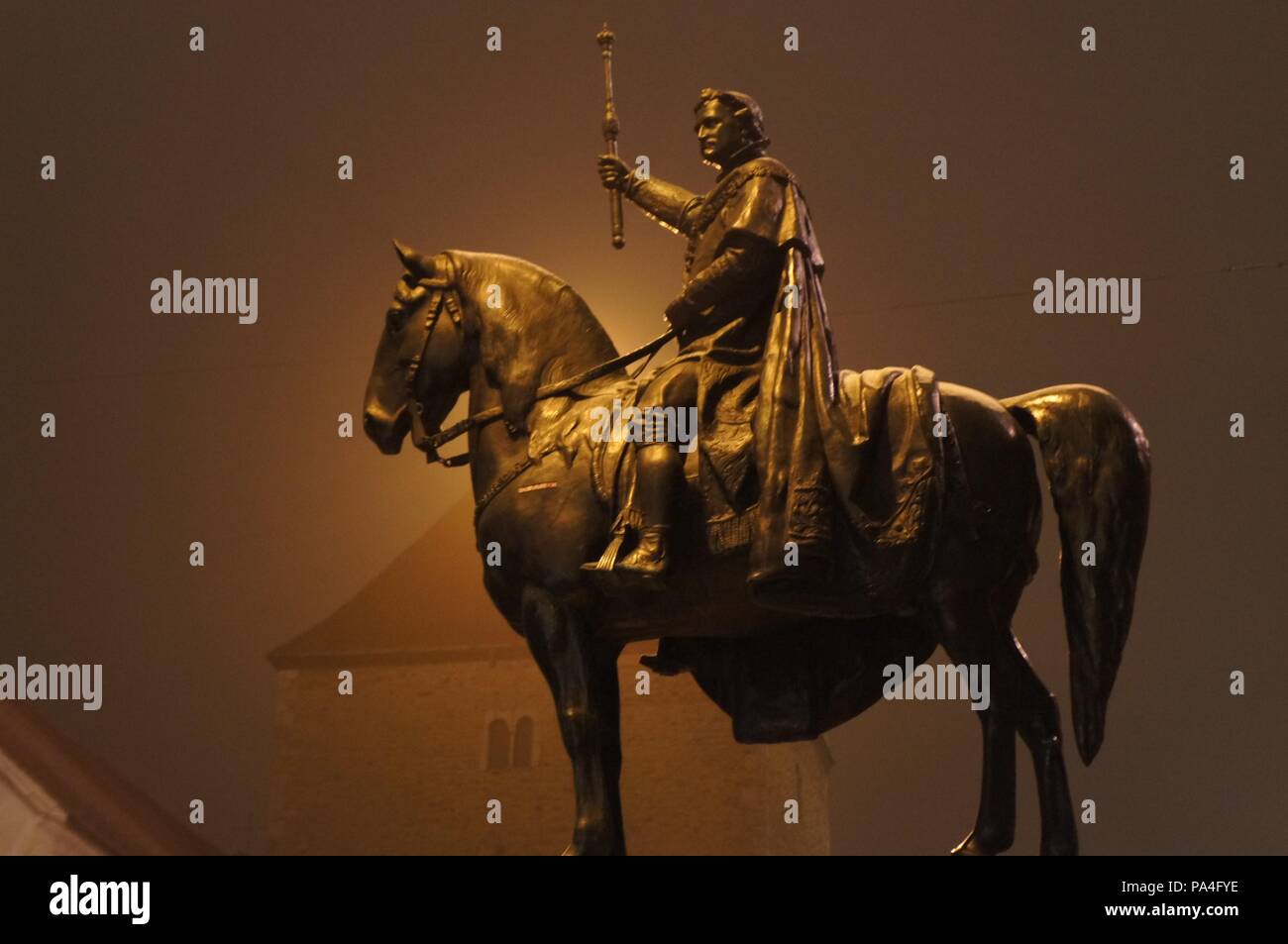 La brume enveloppe la statue d'un cheval et le cavalier sur un soir de décembre froid à Regensburg, Allemagne avec une silhouette d'un bâtiment à l'arrière-plan Banque D'Images