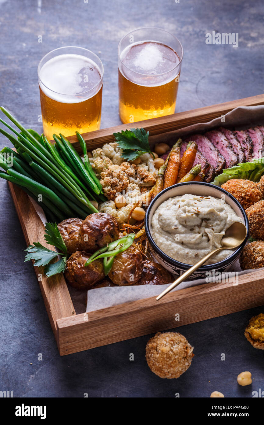 Le pastrami, falafel, babagahanoush, légumes et la bière dans une boîte en bois, copyspace. Banque D'Images
