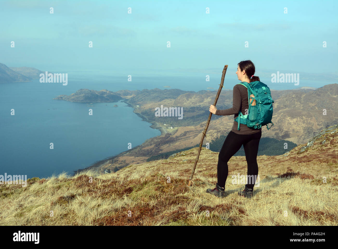 Un female hiker avec bâton de marche sur une montagne Lookout sur Sgurr Coire Choinnichean dans la péninsule de Knoydart, Highlands, Ecosse, Royaume-Uni. Banque D'Images