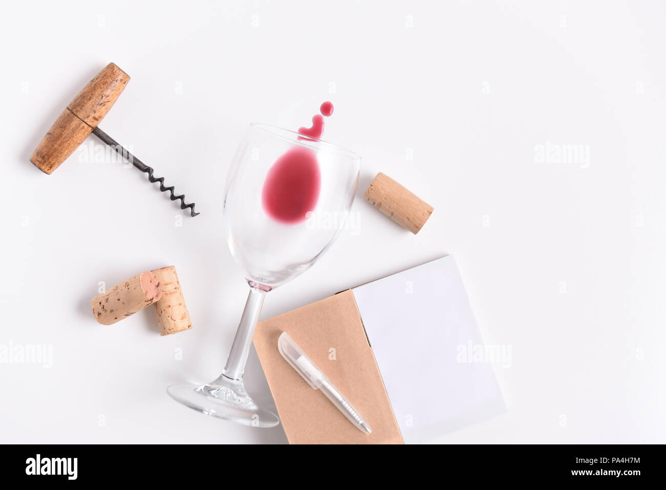 Bloc-notes de dégustation de vin avec un stylo sur la couverture. Tire-bouchon et un verre et bouchons sur blanc avec copie espace. Banque D'Images