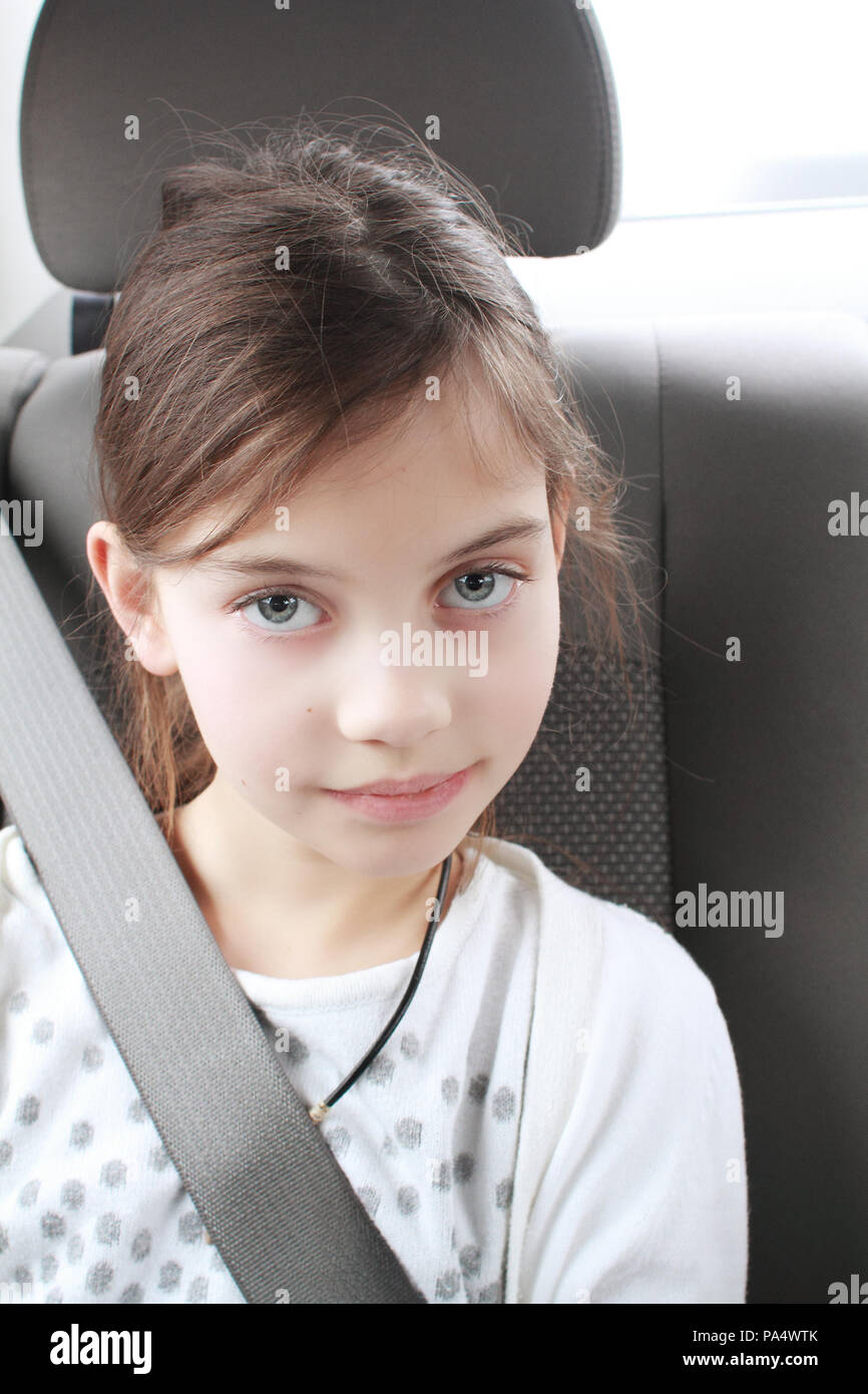 Portrait of cute jeune fille d'âge élémentaire sitting in car-port de la ceinture de sécurité. Concept de la sécurité des transports de l'enfant. Banque D'Images