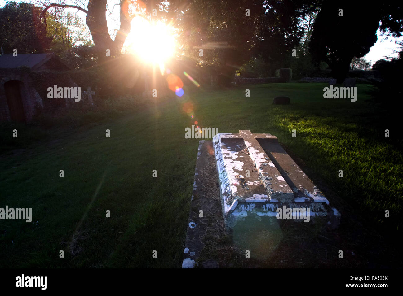 Sunbeam illuminant une tombe dans un cimetière de l'église paroissiale. Banque D'Images