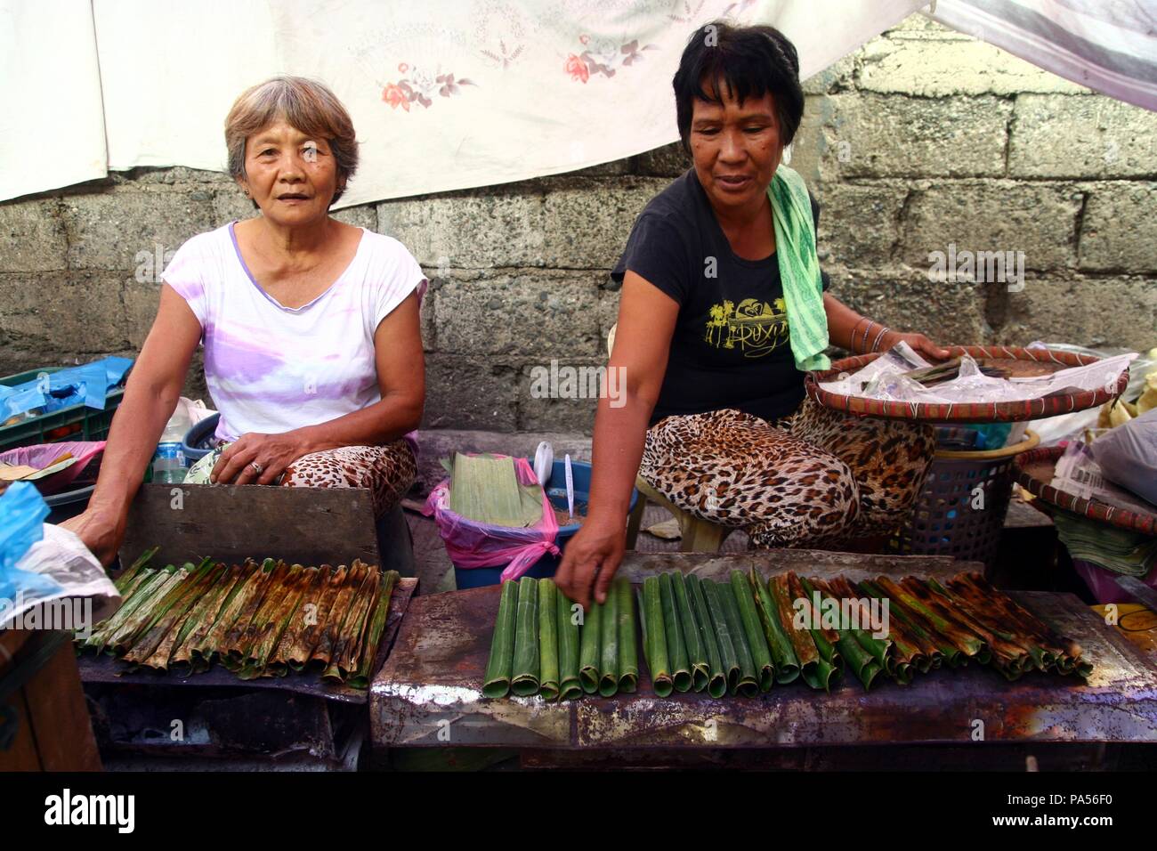 La ville d'Iloilo, PHILIPPINES - le 29 octobre 2015 : marché fournisseurs proposent des collations, connu sous le nom de 'tupig' qui est fait de terre et cuit à glutenous ric Banque D'Images