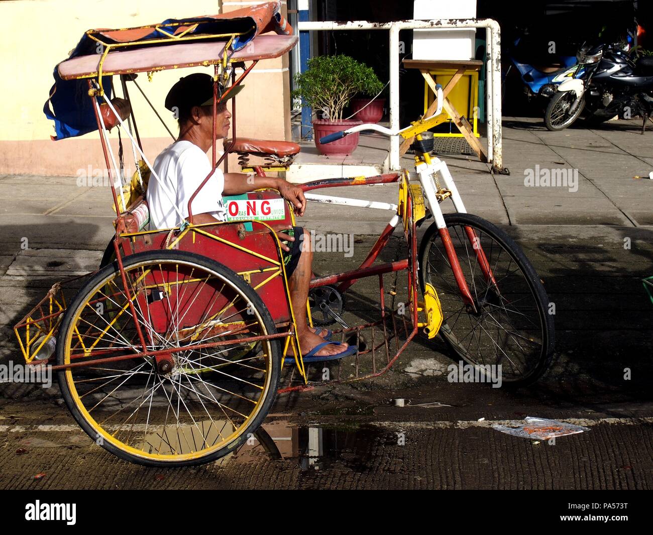 TACLOBAN CITY, PHILIPPINES - le 9 novembre 2015 : un conducteur et son tricycle à pédales pour attendre les passagers le long d'une rue. Banque D'Images