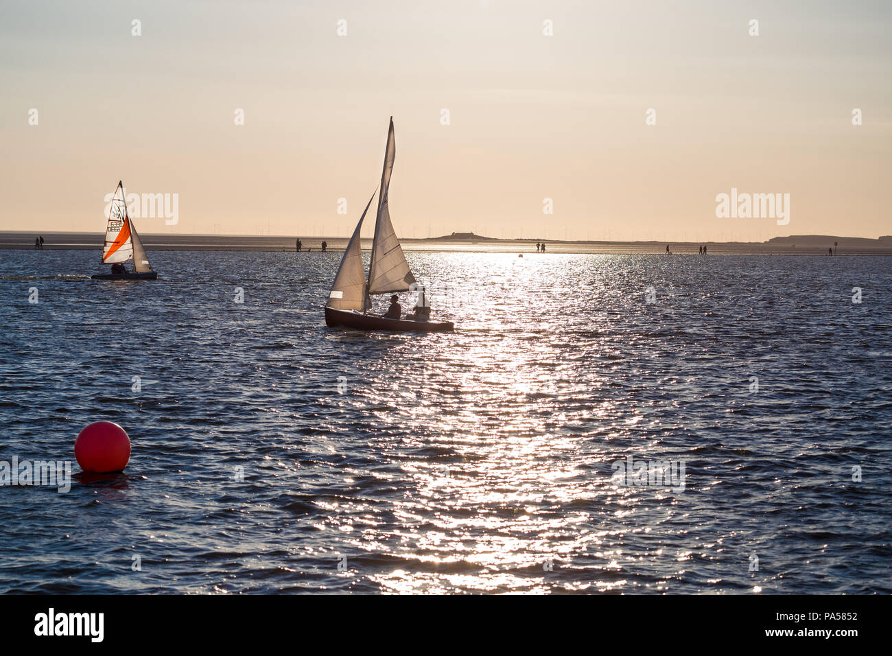 Les voiliers sur le lac marin, West Kirby, Wirral, avec la lumière du soleil sur l'eau ondulante et îles dans l'arrière-plan Banque D'Images