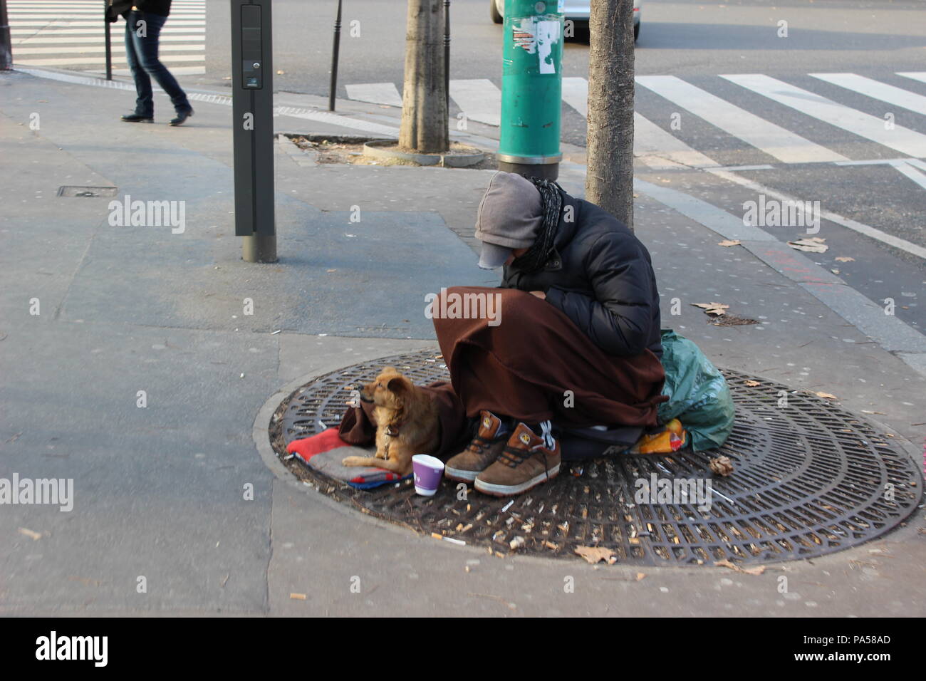 Un homme pauvre et son chien s'asseoir dans la rue de Paris, dans l'attente de l'aide. Banque D'Images