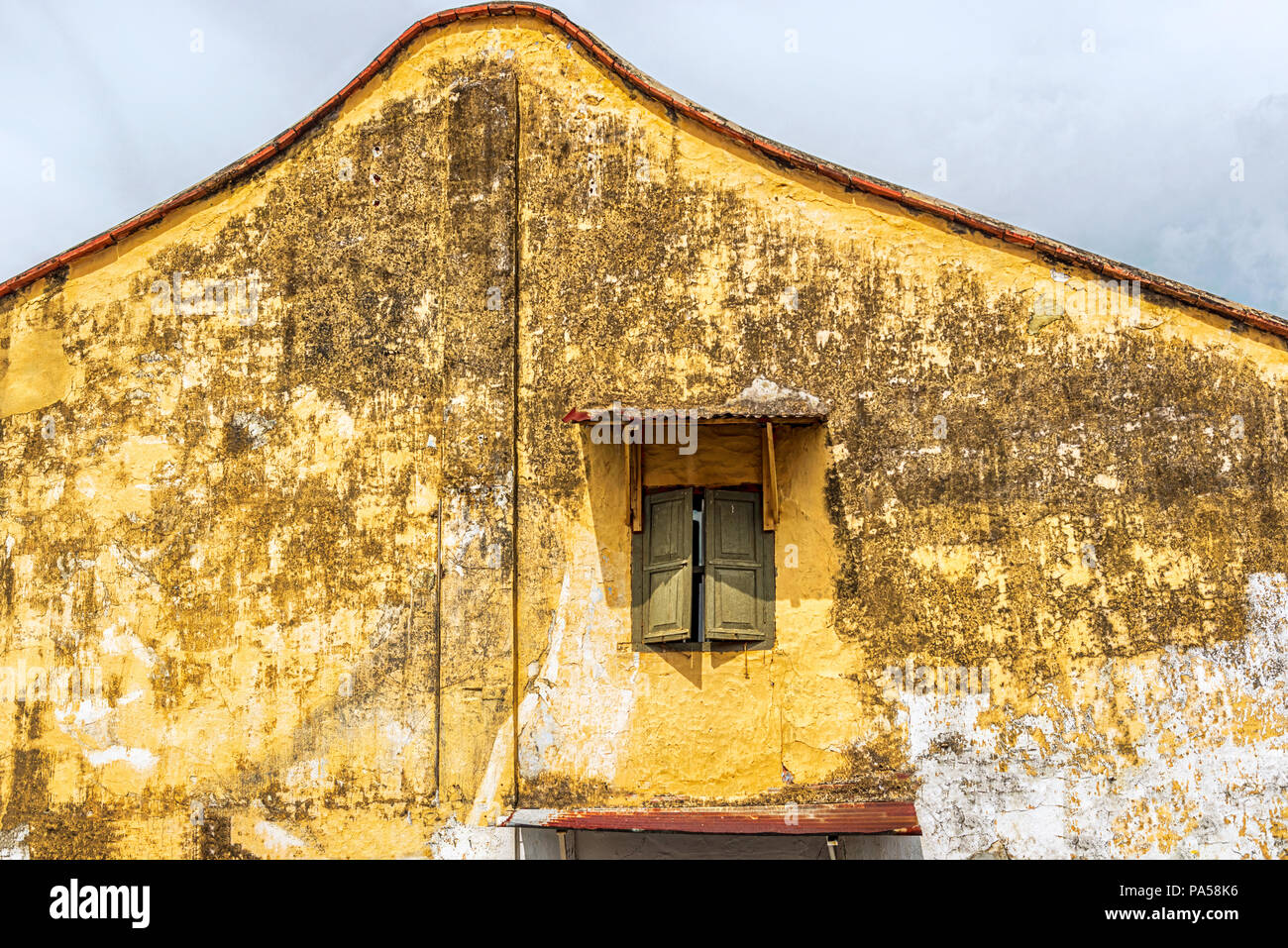 Mur côté coloré de l'ancien bâtiment colonial avec une fenêtre avec volets Banque D'Images