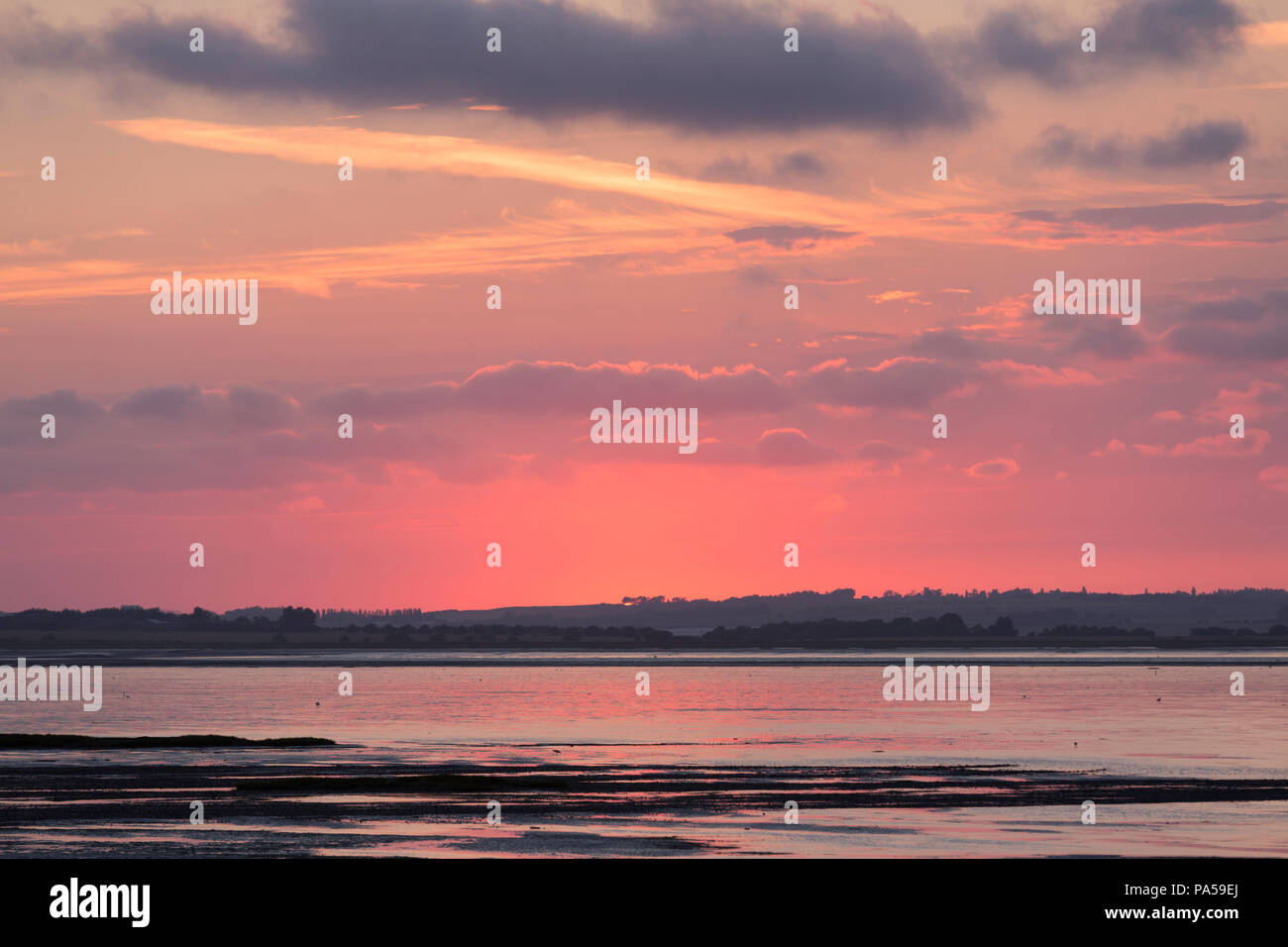 Soleil rose pris de Seasalter, Whitstable, Kent, UK à l'estuaire de l'autre côté de la rigole de l'égard de l'île de Sheppey. Banque D'Images