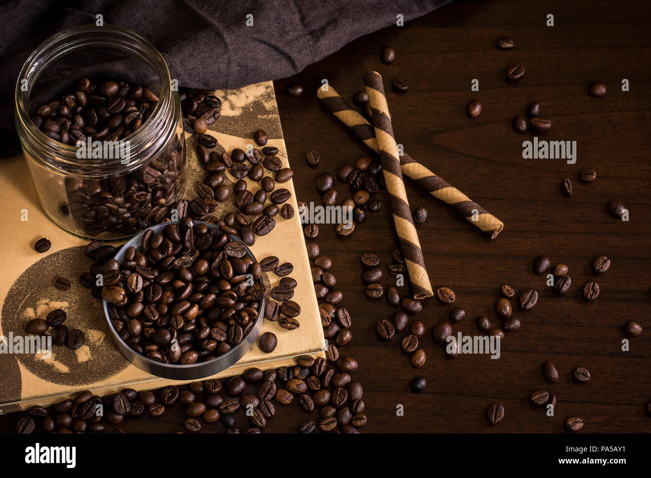 Pot de café en grains divisés sur la table en bois avec des pailles de gaufrette au chocolat Banque D'Images