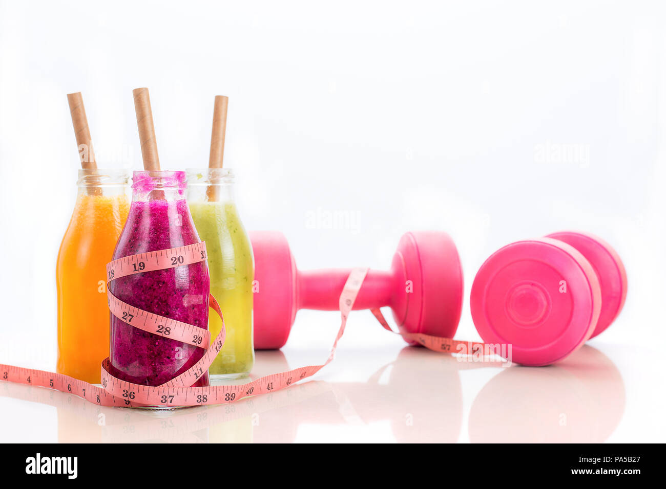 Jus de fruit dans le flacon en verre avec mètre à ruban enroulé autour de la main et poids - alimentation saine et exercice physique concept. Banque D'Images