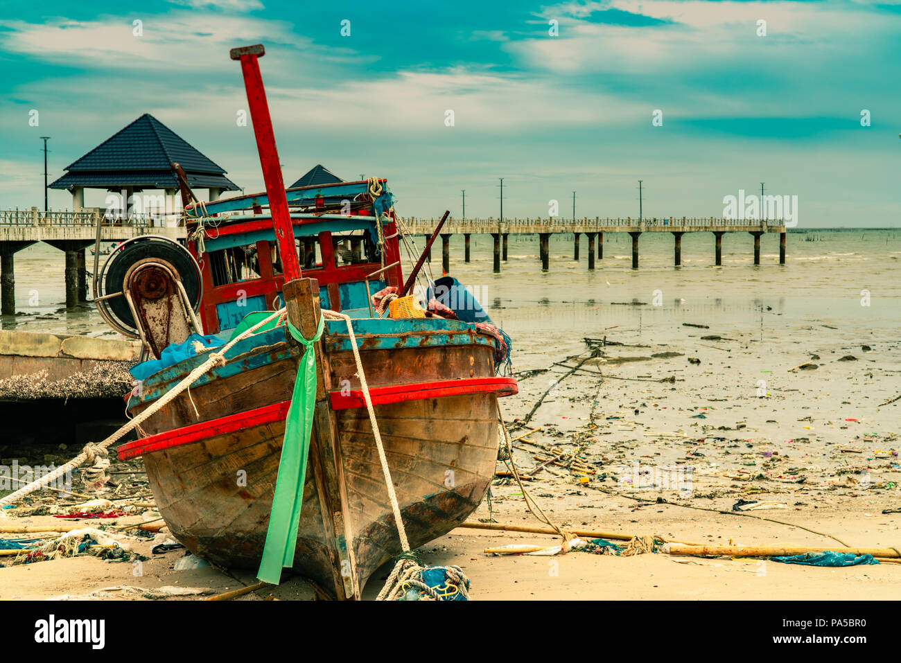 Bateau de pêche sur la plage de sable, près du pont et de la mer. Relaxation sur paradise tropical beach resort et concept. Des ordures sur la plage. Environnement côtier Banque D'Images