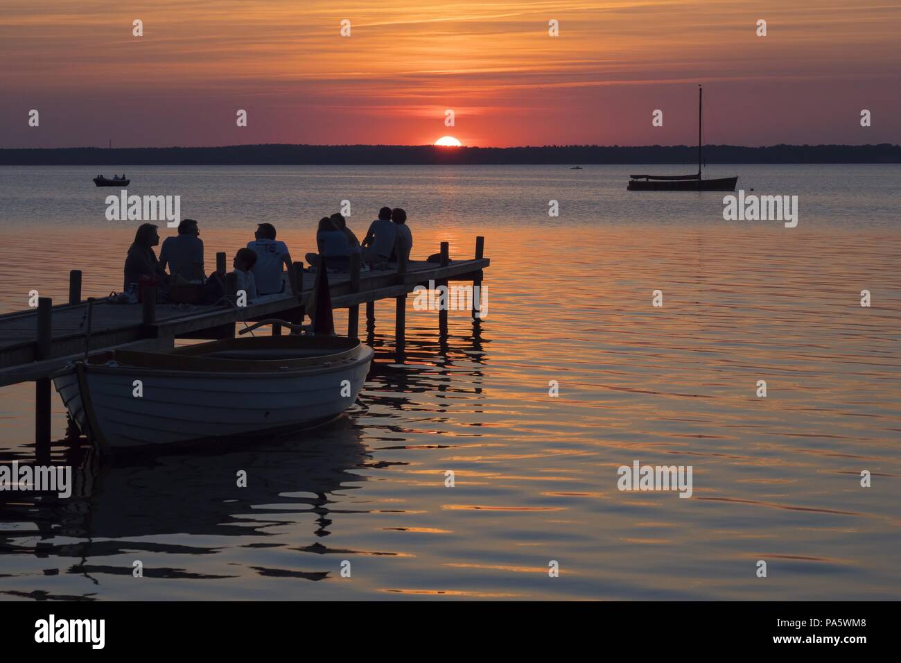 Silhouette de personnes sur un quai pendant le coucher du soleil sur le lac Steinhude, Steinhude, Basse-Saxe, Allemagne Banque D'Images